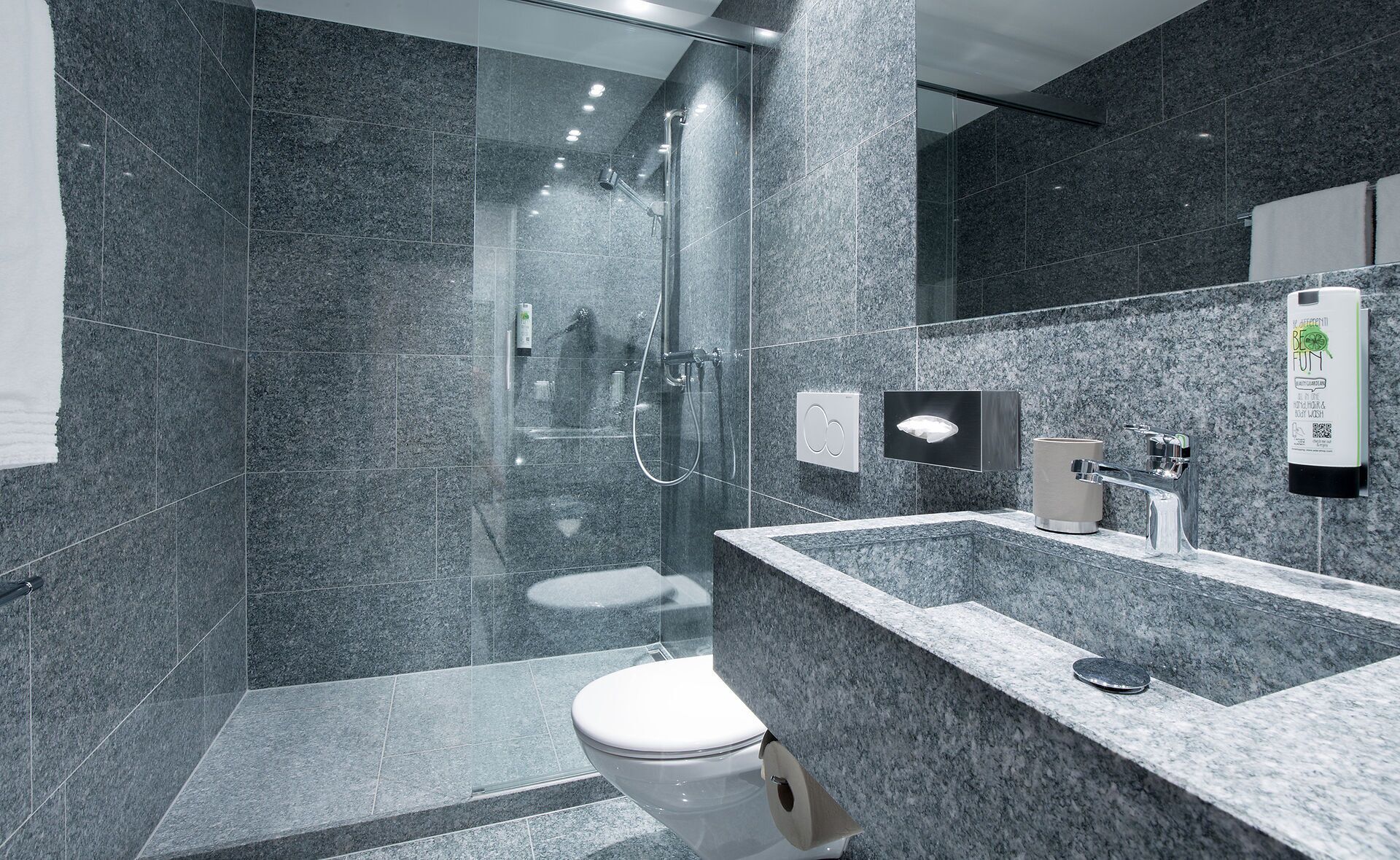 A modern bathroom with a glass-enclosed shower, a marble sink, and a toilet.