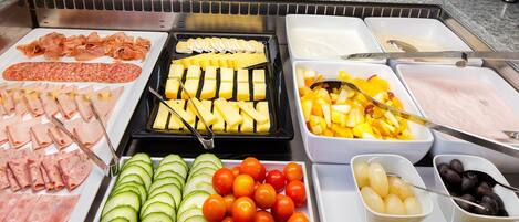 Ein Buffet mit einer Auswahl an Speisen, darunter Fleisch, Käse, Obst und Gemüse.