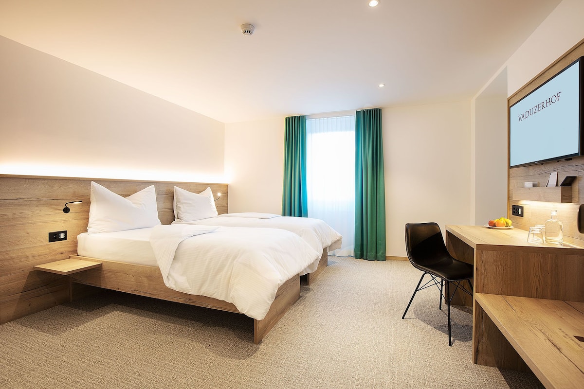Une chambre d’hôtel moderne avec un lit en bois, un bureau et une chaise.