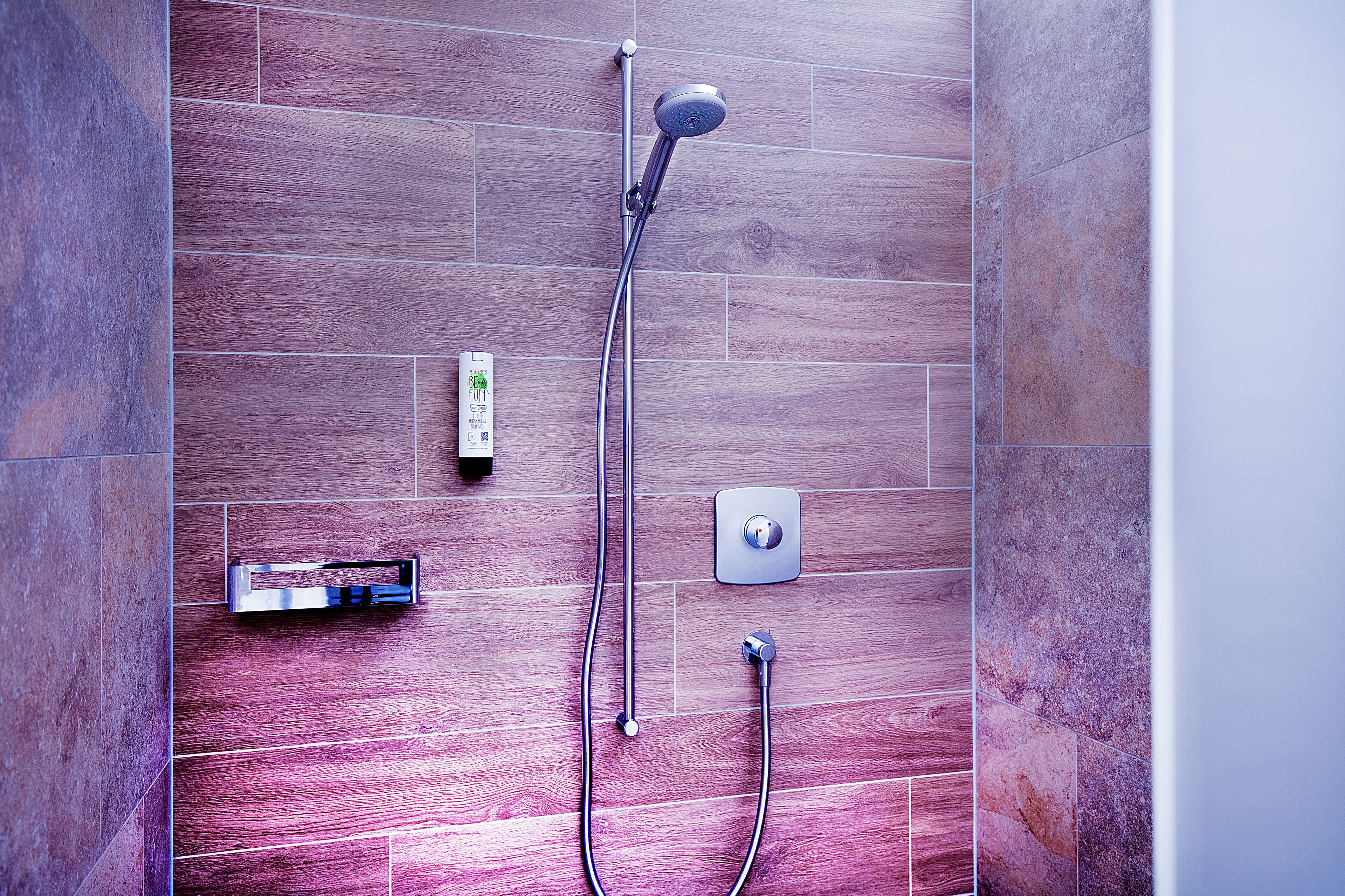 Una ducha moderna con cabezal de ducha manual y panel de control en la pared.