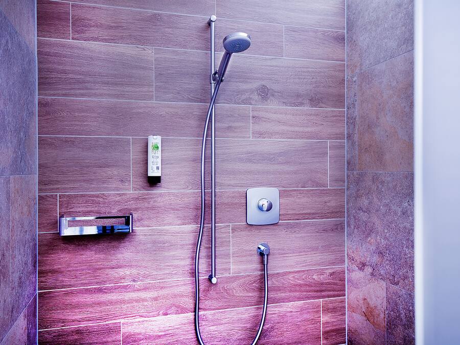 Una ducha moderna con cabezal de ducha manual y panel de control en la pared.