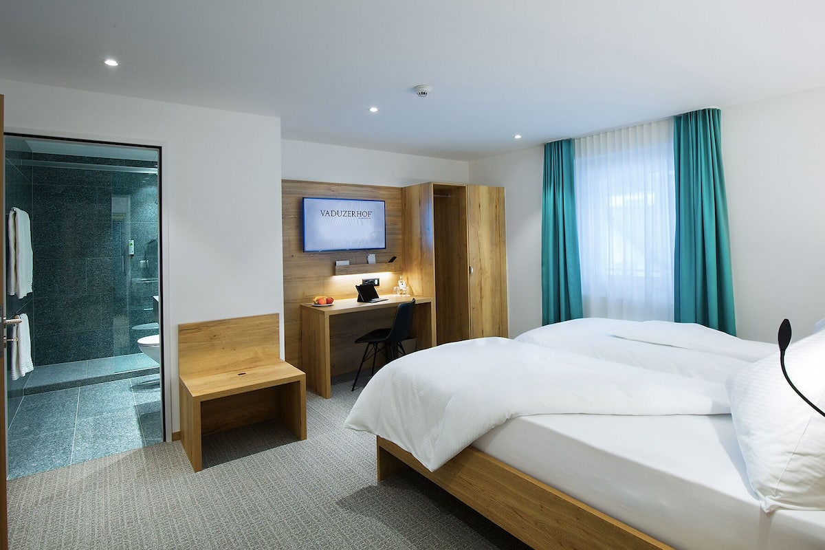 Une chambre d’hôtel équipée d’un lit, d’un bureau, d’une douche et d’une télévision.
