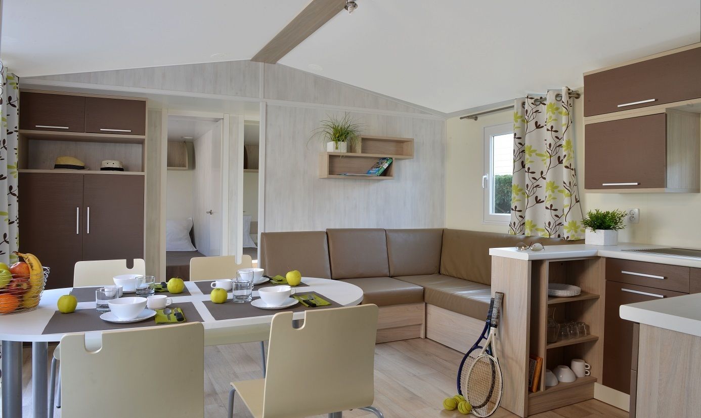 A modern kitchen with a dining area, featuring a built-in bench, a tennis racket, and a variety of kitchen utensils.