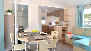 Een compacte leefruimte met een eethoek, kitchenette en een bank met bloemenprint.