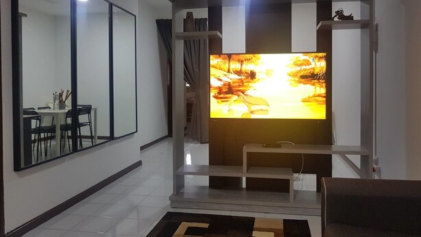A modern living room with a flat-screen TV mounted on a white entertainment unit, a ceiling fan, and a dining area with a table and chairs. - Araaz Homestay (Seremban)