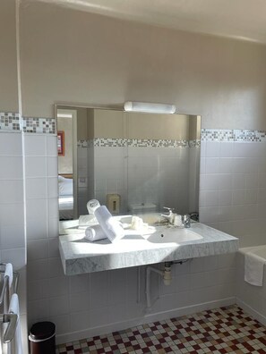 A bathroom with a marble sink, a mirror, and a checkered floor. - Hotel Regina (Sète)