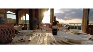 Une table dressée pour le dîner, avec une bouteille de vin Solaiat, des verres et des assiettes, offrant une vue panoramique.