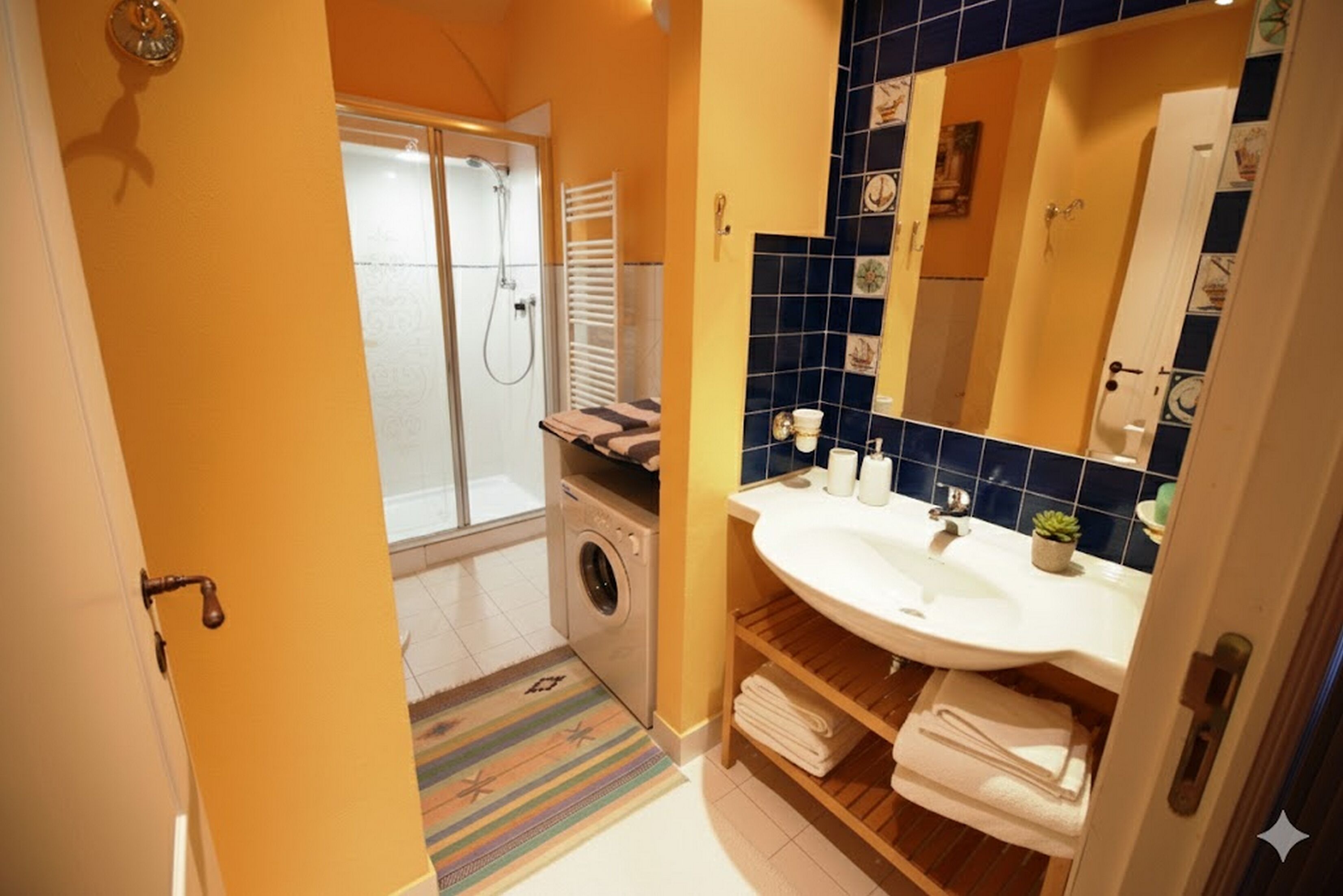 A bathroom with a washing machine, a sink, and a mirror.