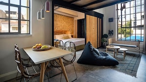 Una habitación moderna con comedor, cama y zona de estar con vistas al exterior.
