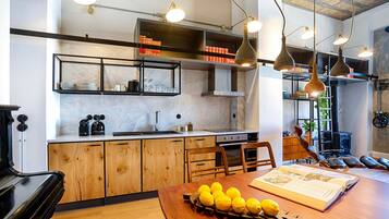 A modern kitchen with wooden cabinets, a dining table with lemons, and pendant lighting.