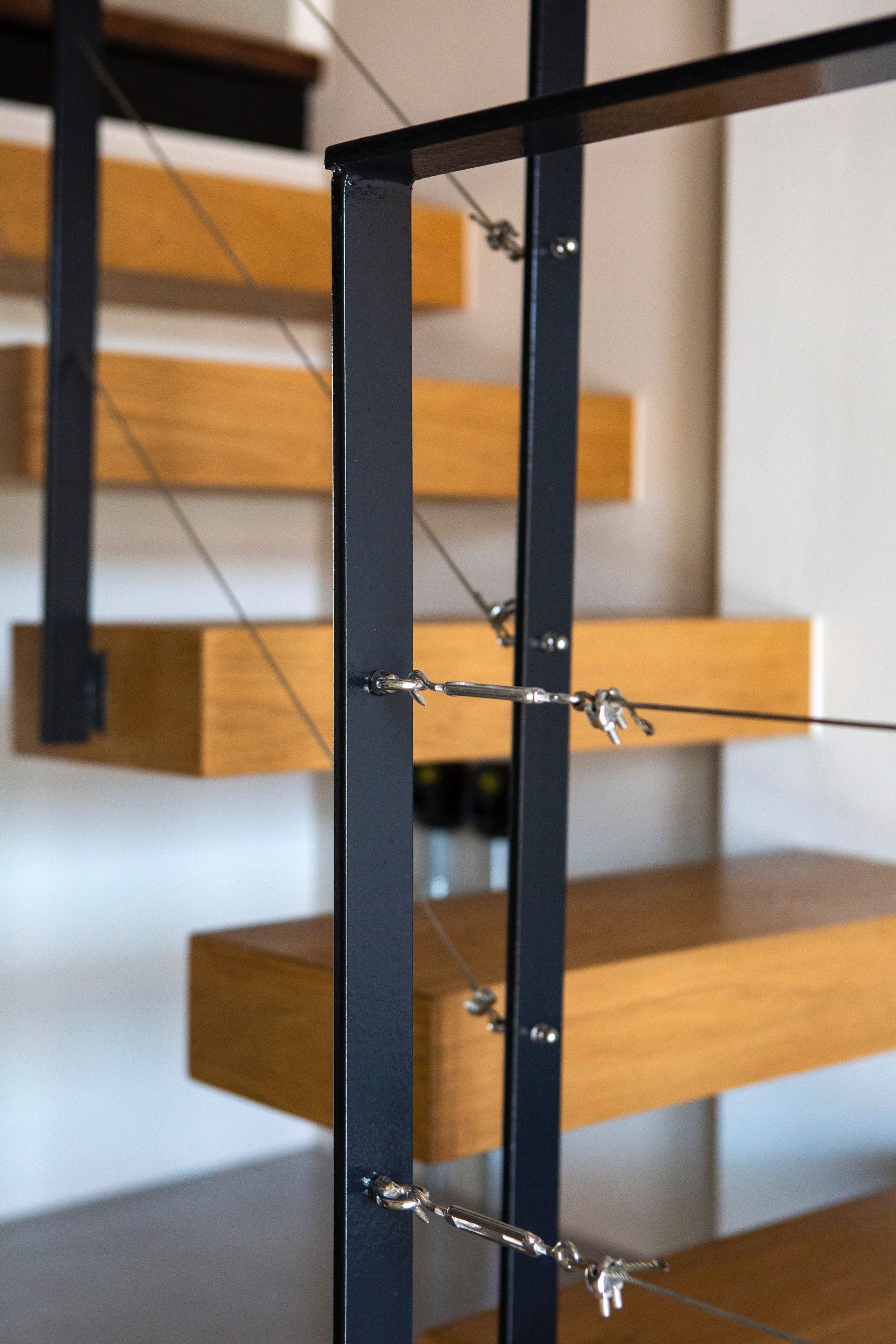 Eine moderne Treppe mit Holzdielen und einem schwarzen Metallgeländer.