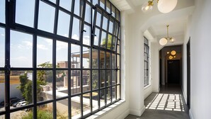 Un pasillo con ventanas amplias, un rellano y una puerta al final.