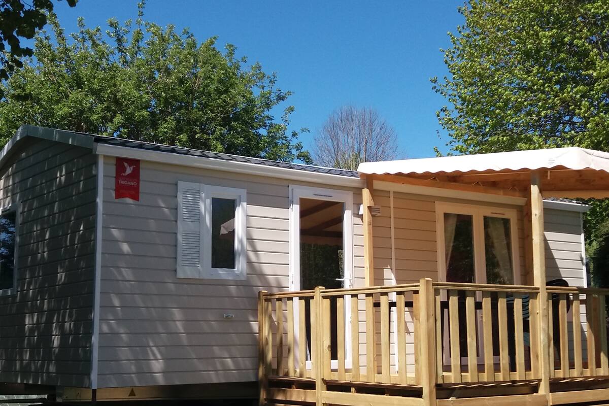 Een stacaravan met een houten terras en een overdekte veranda.