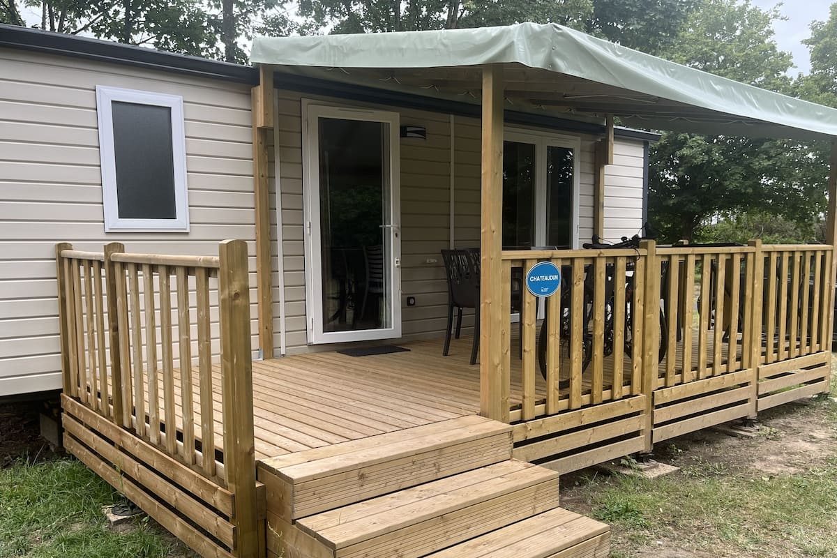 Een stacaravan met een houten terras, een overdekte veranda en een schuifpui.