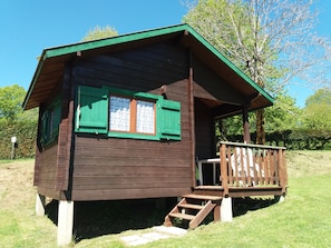 A small wooden cabin with a balcony and a set of stairs leading to the entrance. - Camping de Tauves (Tauves)