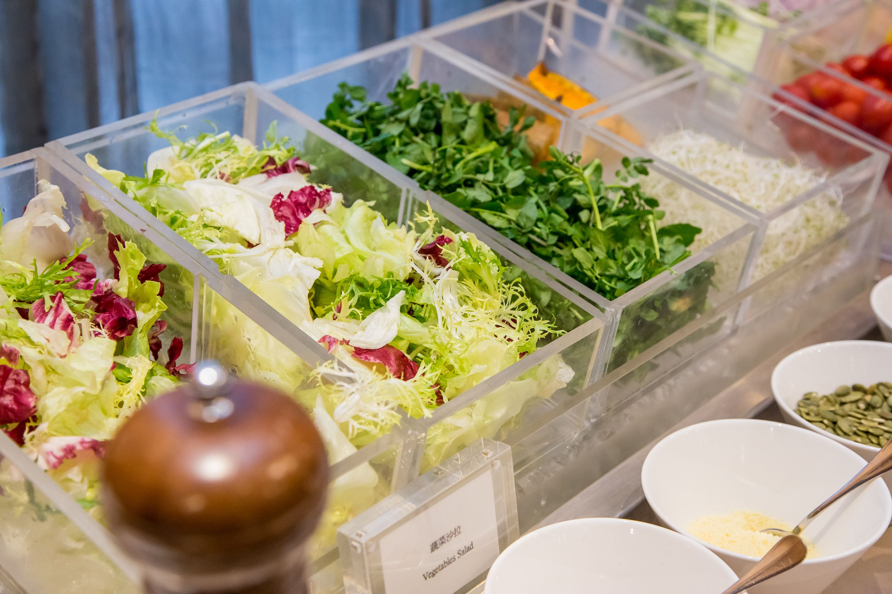 A salad bar with various fresh vegetables and greens.
