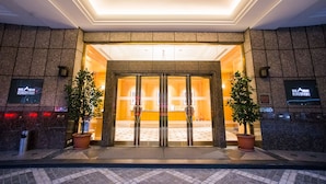 Een hotelentree met een glazen deur, plantenbakken en een betegelde vloer.
