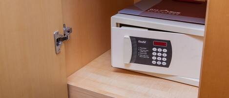 A safe with a keypad and a red top, placed inside a wooden cabinet.