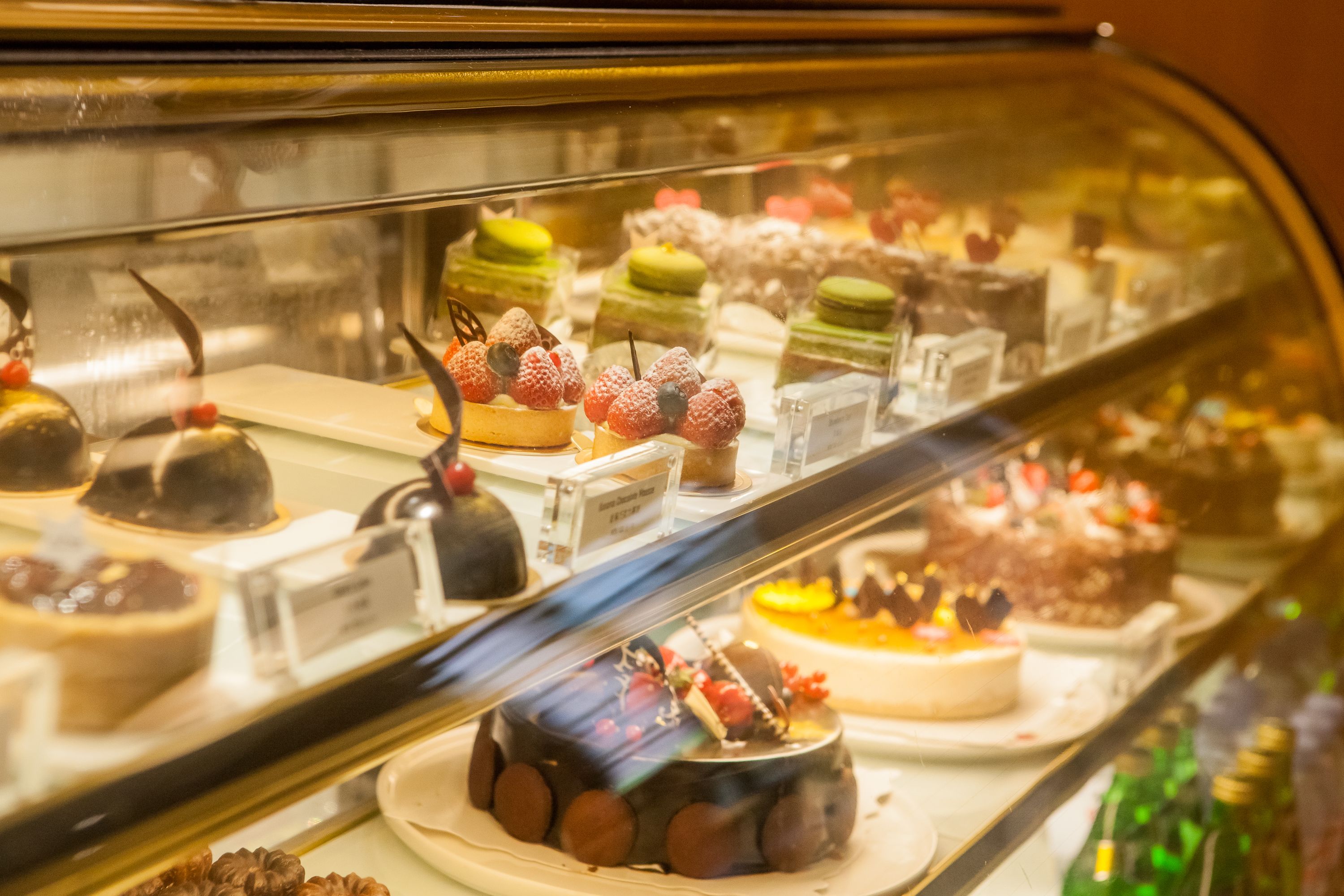 A variety of desserts displayed in a glass case, including cakes and pastries.