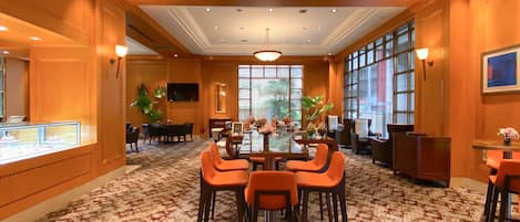 A conference room with a glass table, orange chairs, and a large window with a view of trees.