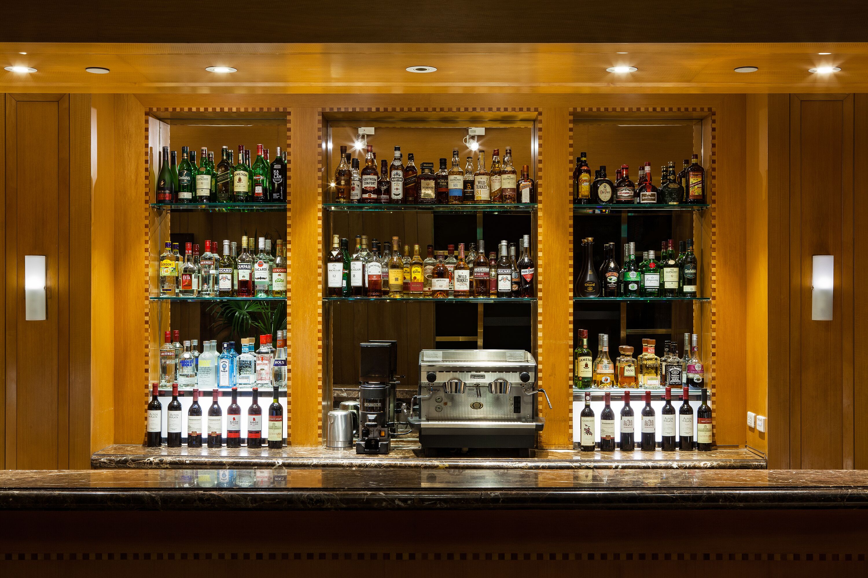 A bar with multiple shelves of liquor bottles and a coffee machine.