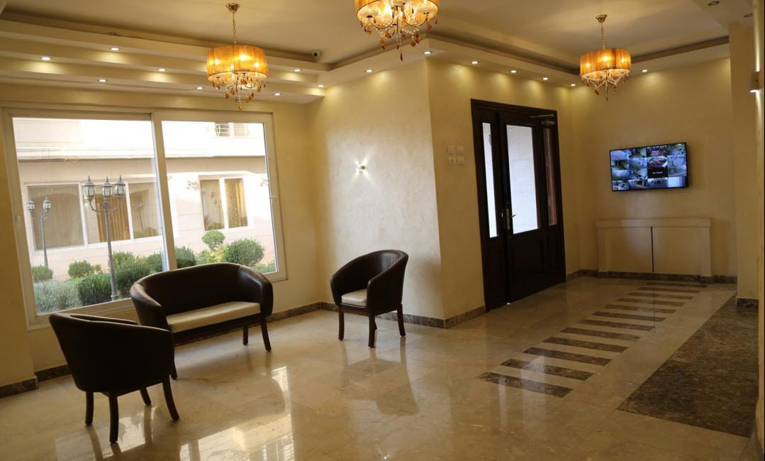 Eine Lobby mit einer Chandelüster, einem Fernseher und einer Sitzecke mit einer Bank und Sesseln.