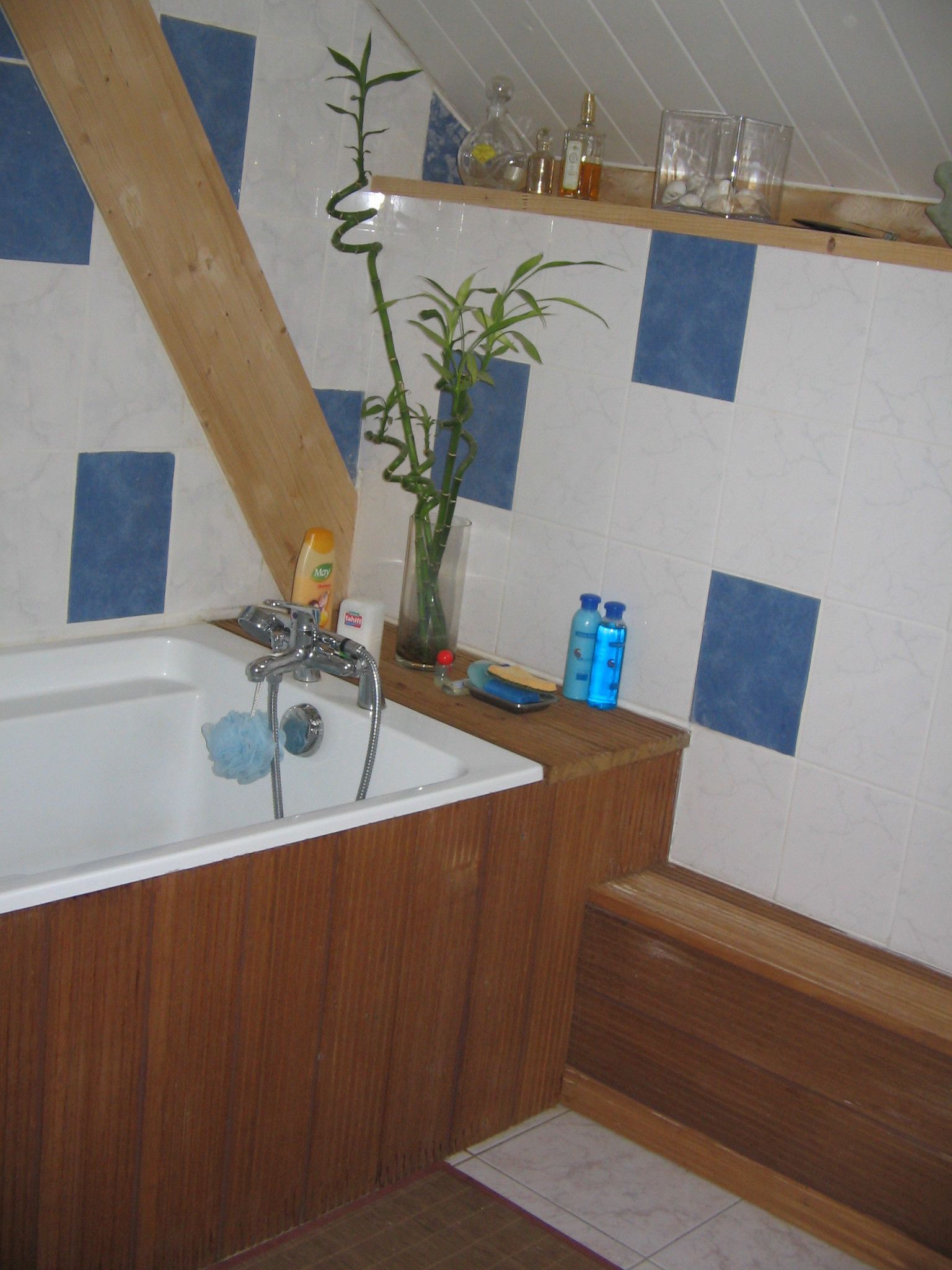 Un baño con tocador de madera, bañera blanca y planta de bambú.