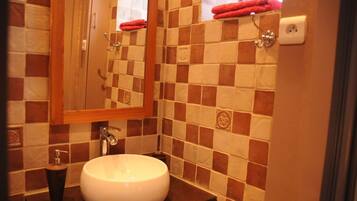 Une salle de bain avec un mur carrelé, un lavabo rond, un miroir et un porte-serviettes.