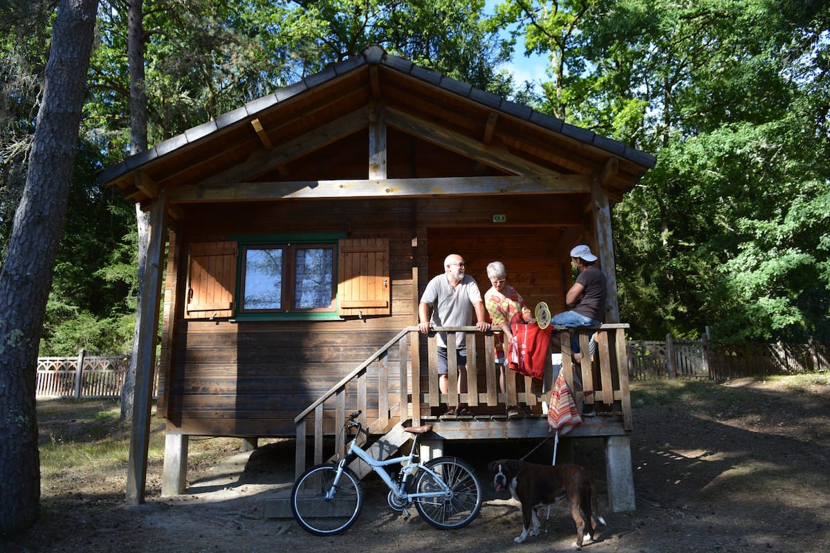 Une cabane en bois avec un porche, un vélo et un chien.