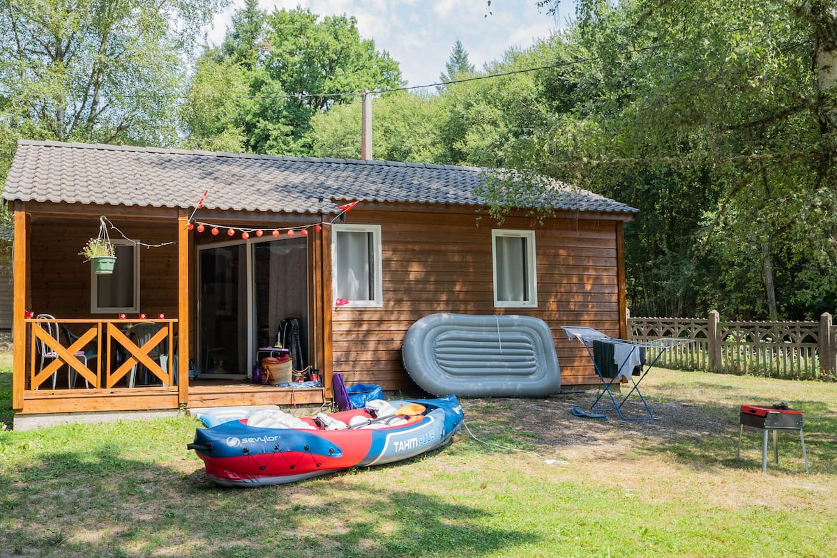 Une cabane en bois avec un porche, un espace extérieur couvert aménagé en salon, et un radeau flottant.