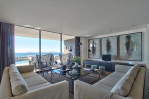 A modern living room with a glass wall, a sofa, a coffee table, and a TV.