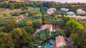 An aerial view of a residential area with houses, a swimming pool, and a river. - Kardaris Villa (Zakynthos)
