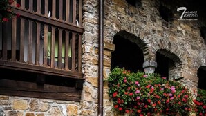 A stone building with a wooden table and benches, surrounded by greenery and flowers. - Affittacamere Nonna Leni (Frisanco)