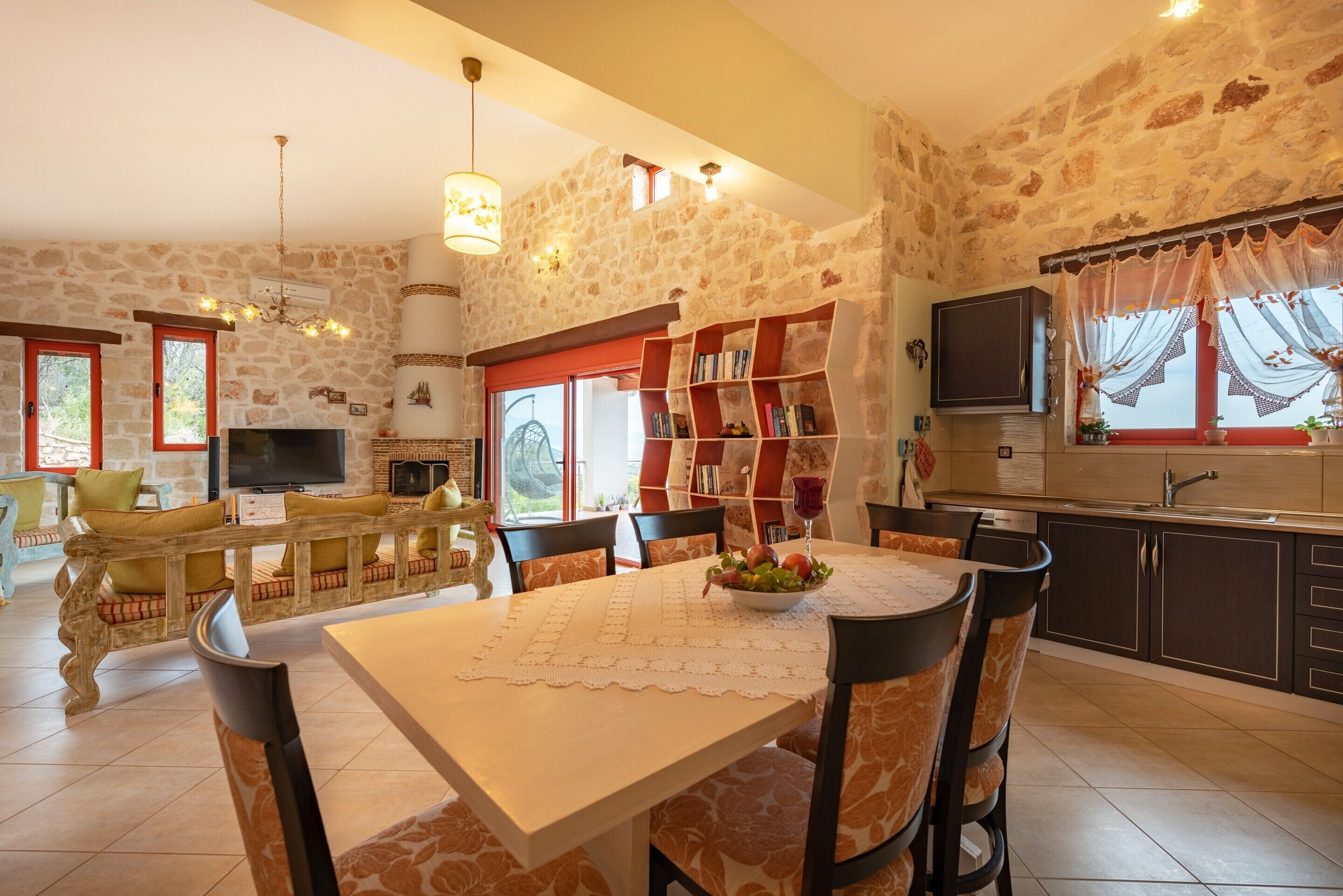Una sala de estar acogedora con una pared de piedra, una chimenea, un televisor y un comedor con mesa y sillas.