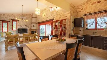 Una sala de estar acogedora con una pared de piedra, una chimenea, un televisor y un comedor con mesa y sillas.