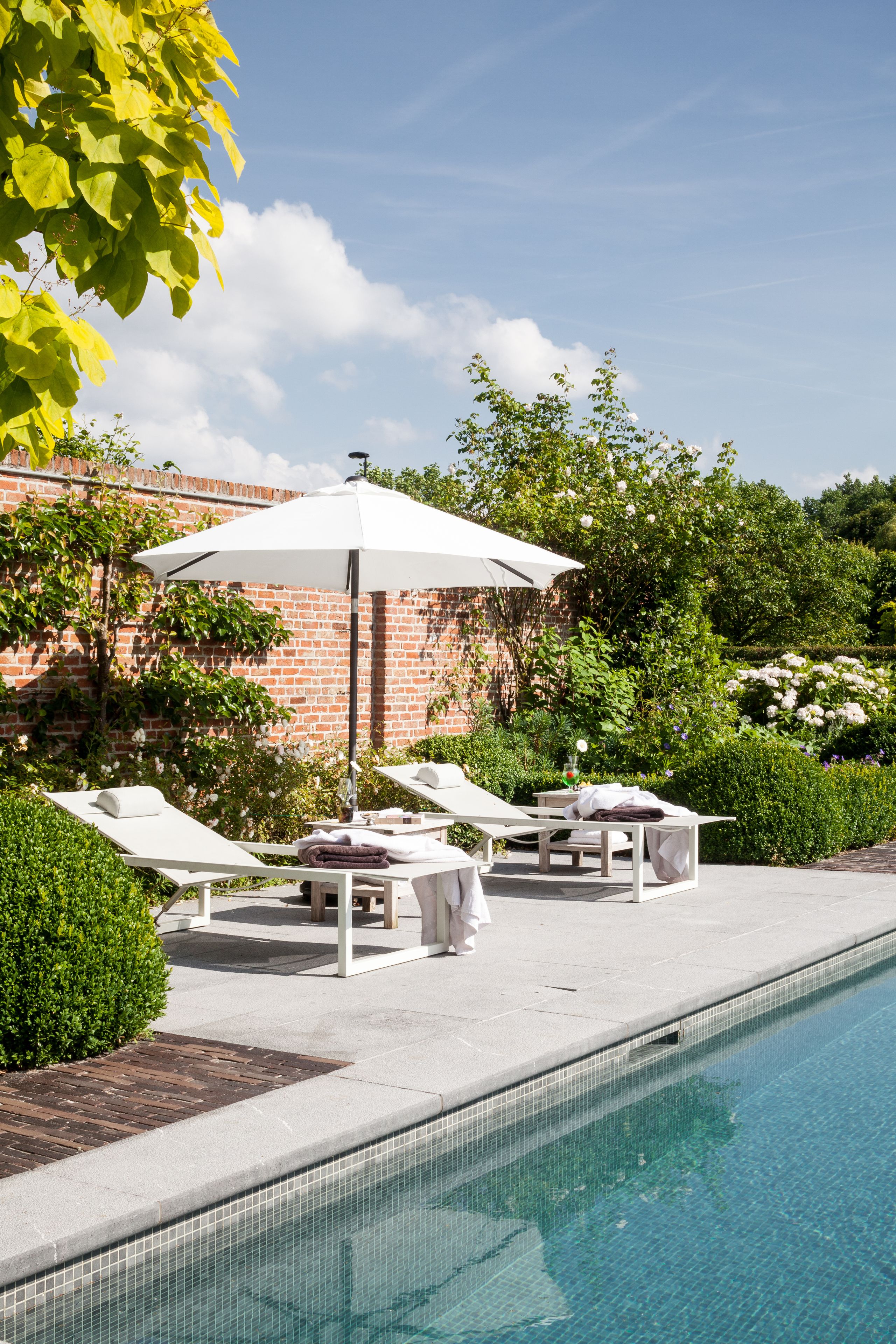 A poolside area with lounge chairs, a table, and an umbrella.
