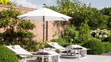 A poolside area with lounge chairs, a table, and an umbrella.