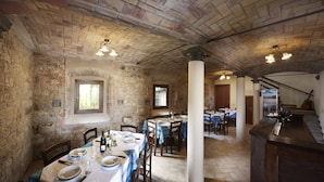 A rustic dining area with stone walls, wooden tables, and a brick ceiling.