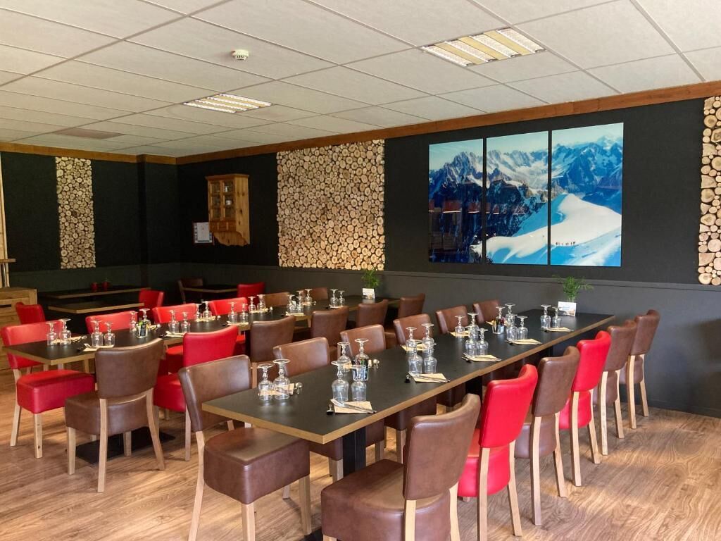 A conference room with multiple tables and chairs, wooden walls, and a large window with a mountain view.