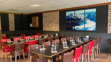A conference room with multiple tables and chairs, wooden walls, and a large window with a mountain view.