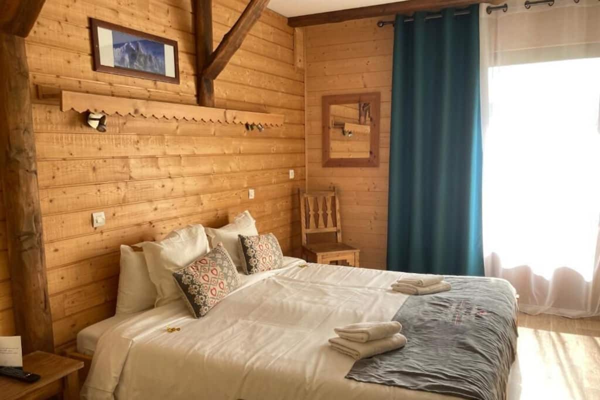 Una habitación de cabaña de madera con una cama, una mesita pequeña y una silla.