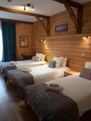 Une cabane en bois avec quatre lits, chacun étant équipé d’oreillers et de couvertures. On y trouve également une petite table et une chaise.