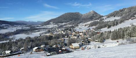 A snow-covered ski resort with buildings, ski slopes, and a mountain backdrop.