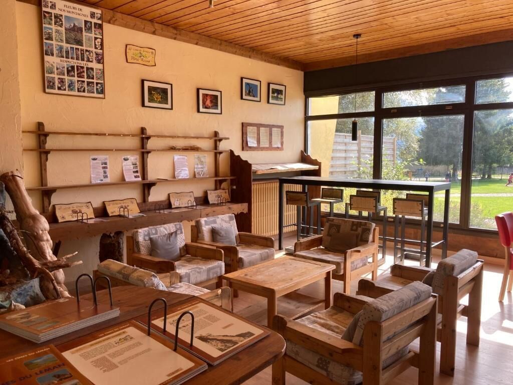 A cozy room with wooden furniture, a large window, and a bulletin board with photos and notices.