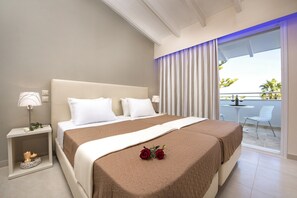A hotel room with a large bed, a bedside table with a lamp, and a view of the balcony. - Onar Corfu Aparts & Studios (Corfu)