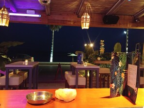 An outdoor dining area with tables and chairs, a wooden ceiling, and a view of the night sky. - Onar Corfu Aparts & Studios (Corfu)