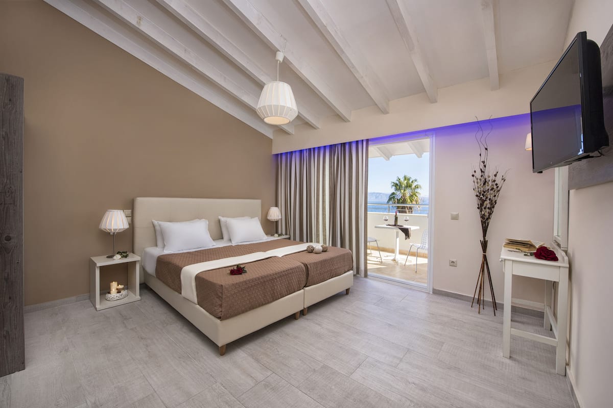 A modern hotel room with a large bed, a television, a small table, and a view of the outdoors.