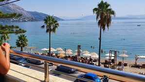 A beachside view with palm trees, umbrellas, and people swimming. - Onar Corfu Aparts & Studios (Corfu)