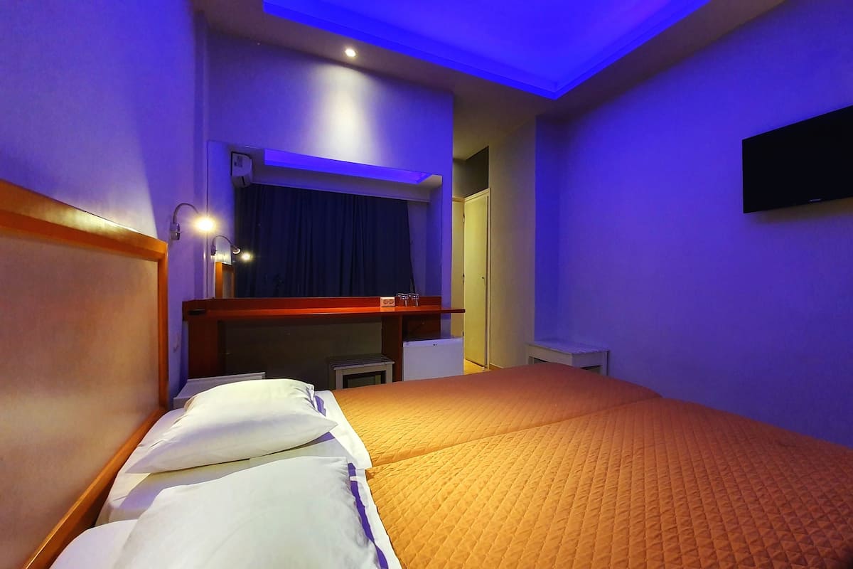 A hotel room with a bed, a desk, a flat-screen TV, and a mirror.