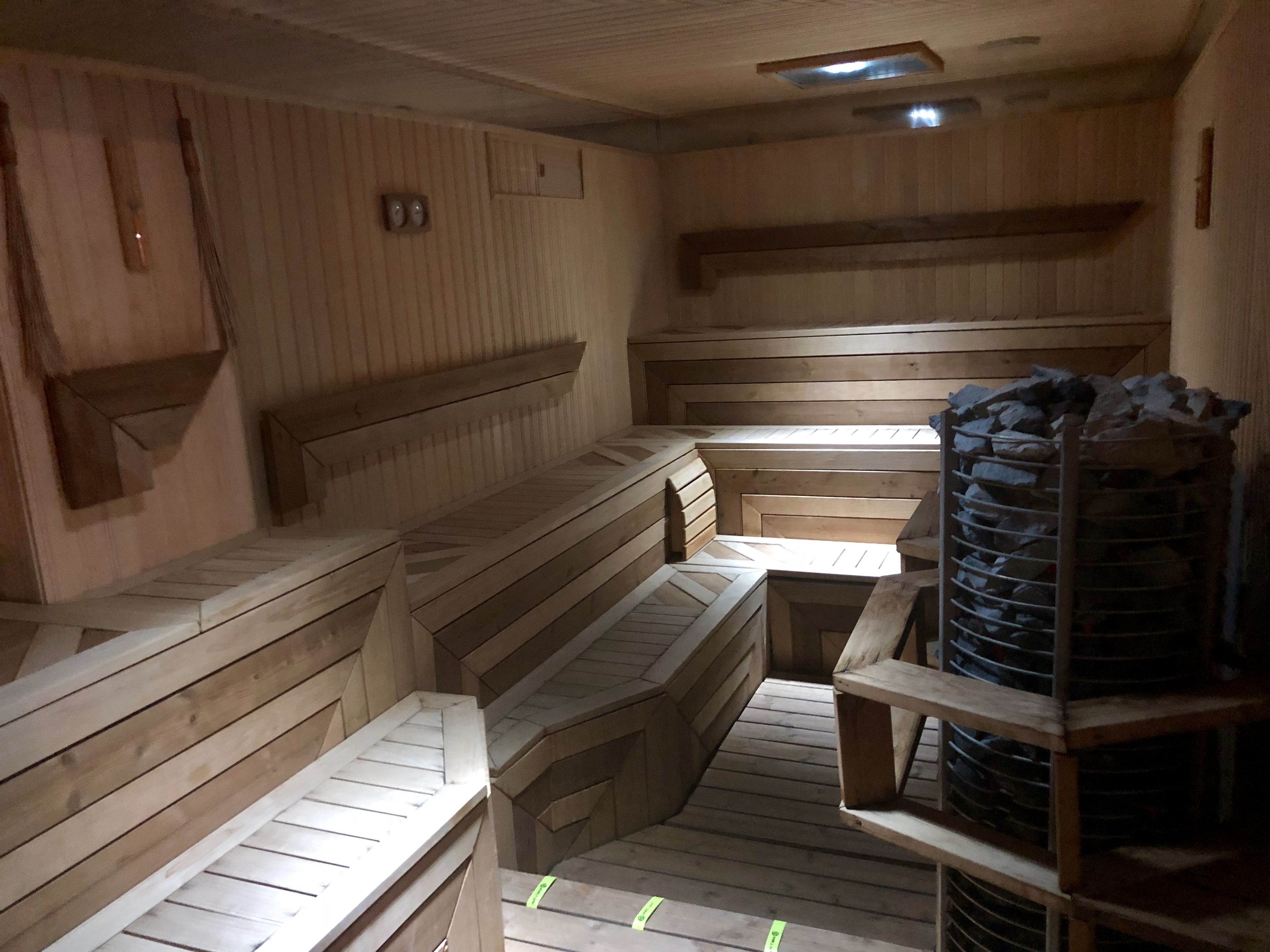 A sauna room with wooden benches and a stone shelf.